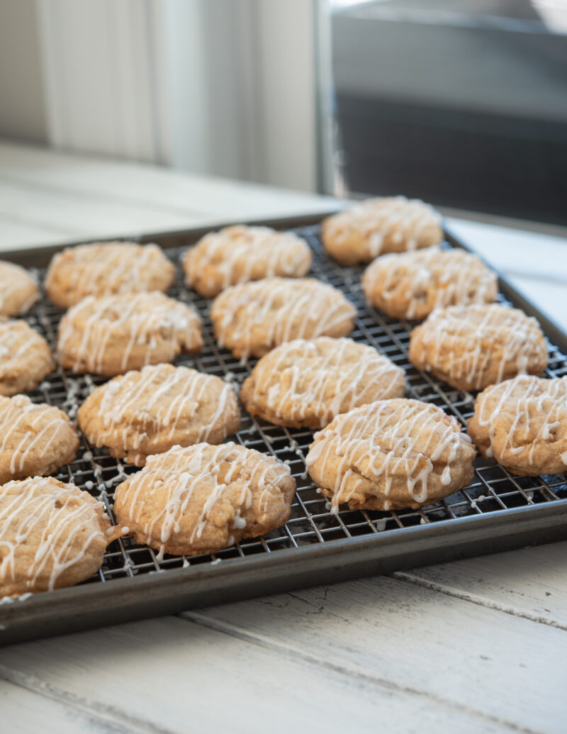 Soft apple cookies are iced on a cookie rack