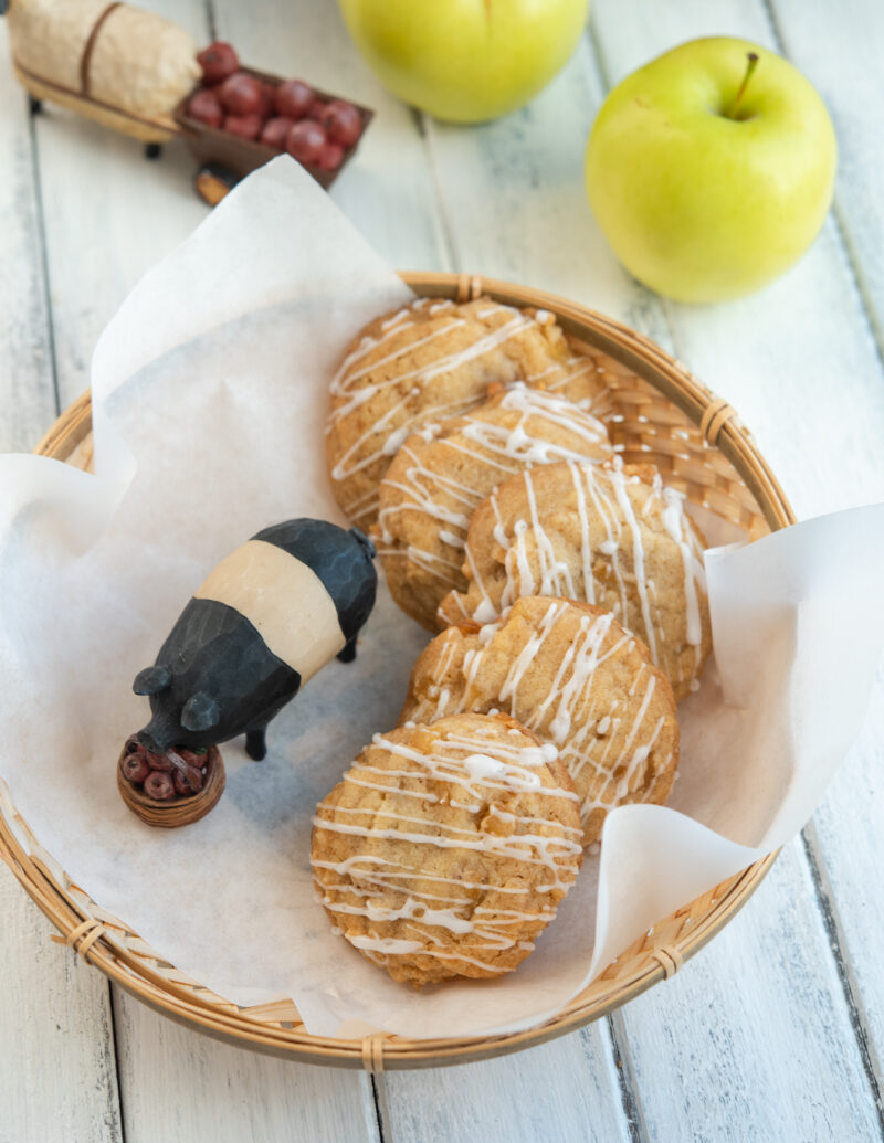 Iced soft apple cookies are in the basket with a pig figurine.