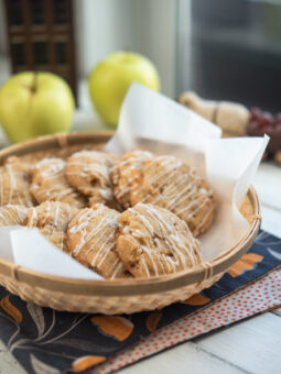 Soft apple cookies are served in a lined basket with apples behind.