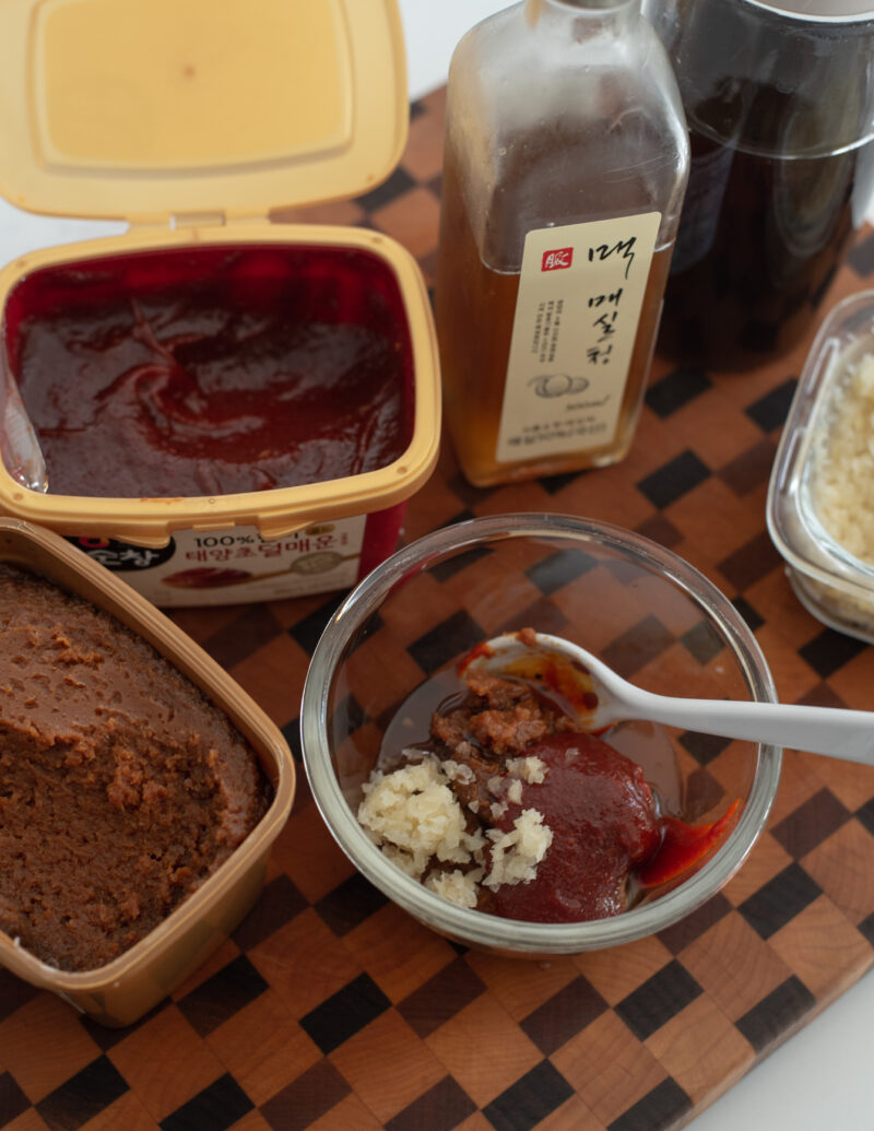 Gochujang and doenjang are combined with other seasonings in a bowl to make ssamjang.