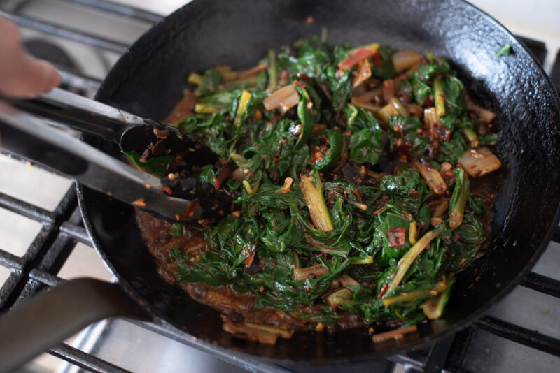 Swiss chard is added to the sauce and combined in a skillet.