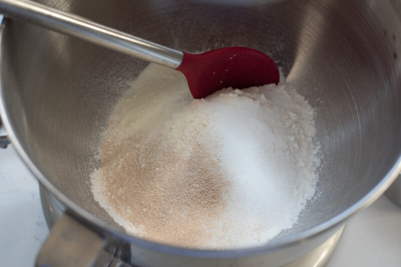Dry ingredients are combined with spoon in a mixer bowl.
