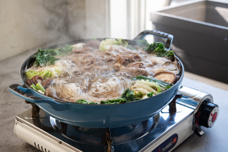 Korean beef and vegetable hot pot is boiling up in the pan over the portable stove.