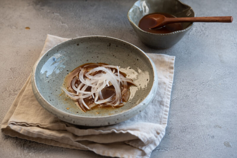 A small serving bowl contains dipping sauce and onion slices.