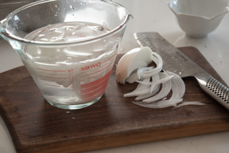 Onion slices are added to cold water to soak.