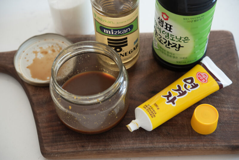 Korean mustard is added to a dipping sauce mixture in a jar.