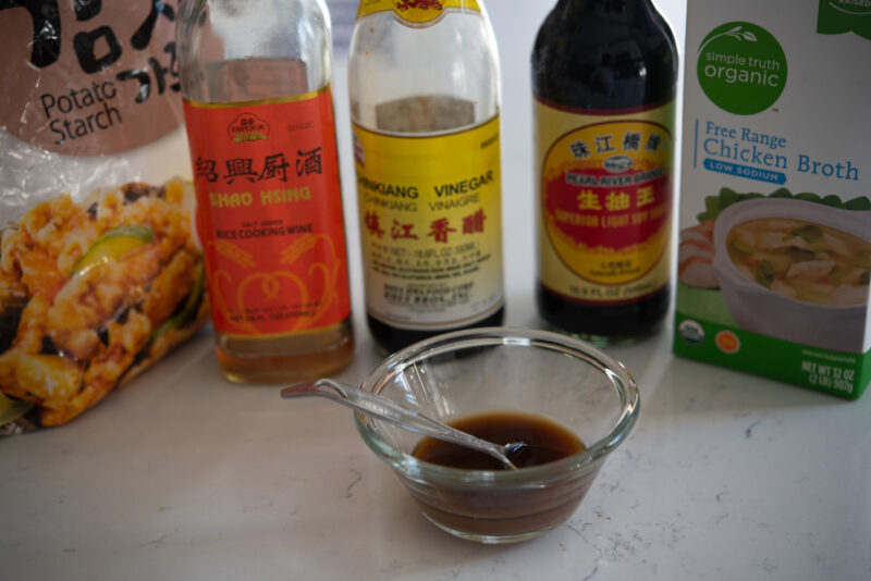 A small bowl with stir fry sauce and the ingredients bottles are showing.