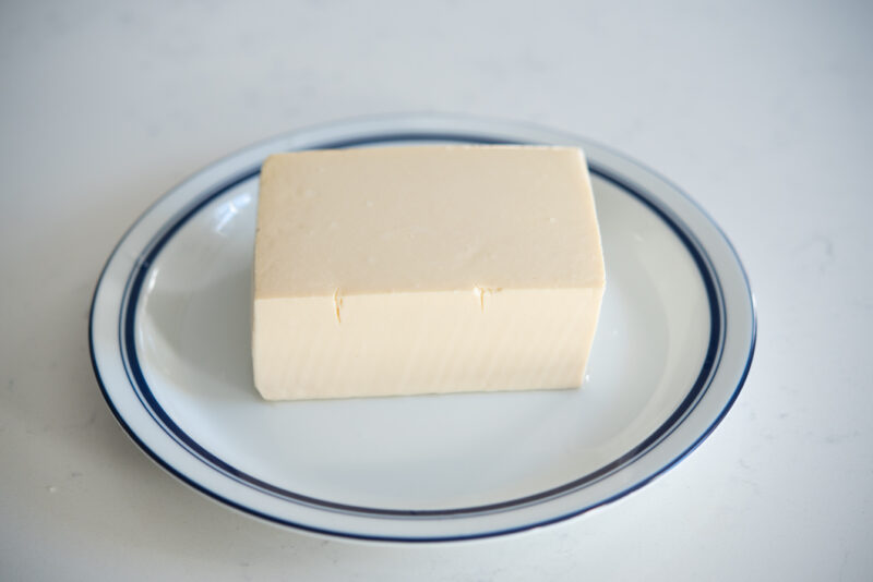 A block of silken (soft) tofu is placed on a plate.