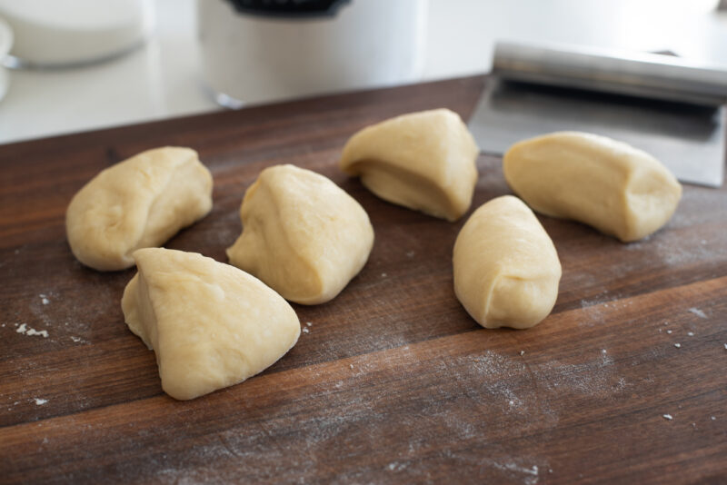 Brioche dough is divided into 6 pieces on the wooden surface.