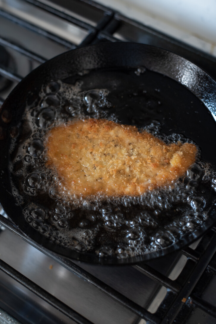 Crispy pork cutlet sizzling in hot frying oil