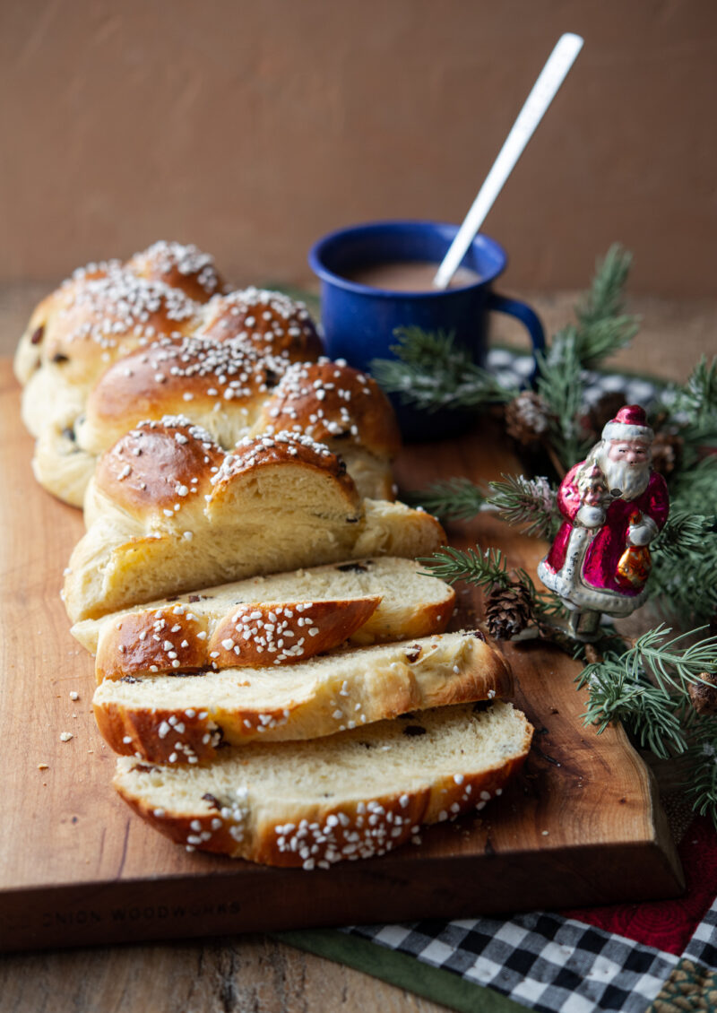 Finnish Pulla bread slices are next to vintage Santa ornament on a greenery and a cup of hot chocolate.