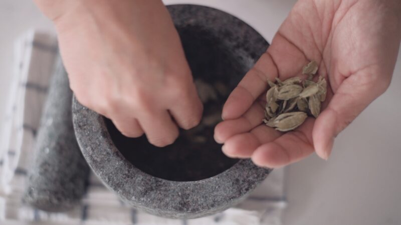 Picking out cardamom pods from the mortar by hand.
