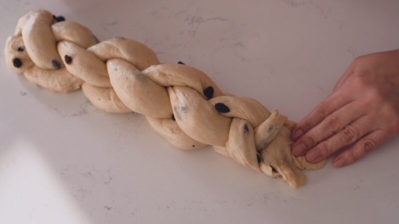 Pinch the ends of braided Pulla dough with a hand.