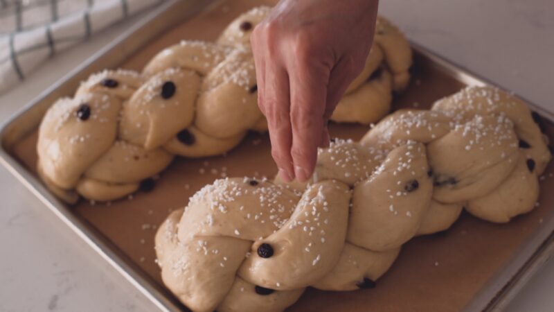 Pearl sugar is sprinkled on top of two braided Pulla loaves.