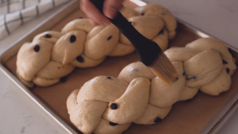 Egg wash is brushed on to braided pulla bread dough.