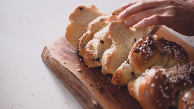 Pulla loaf is being sliced on a cutting board.