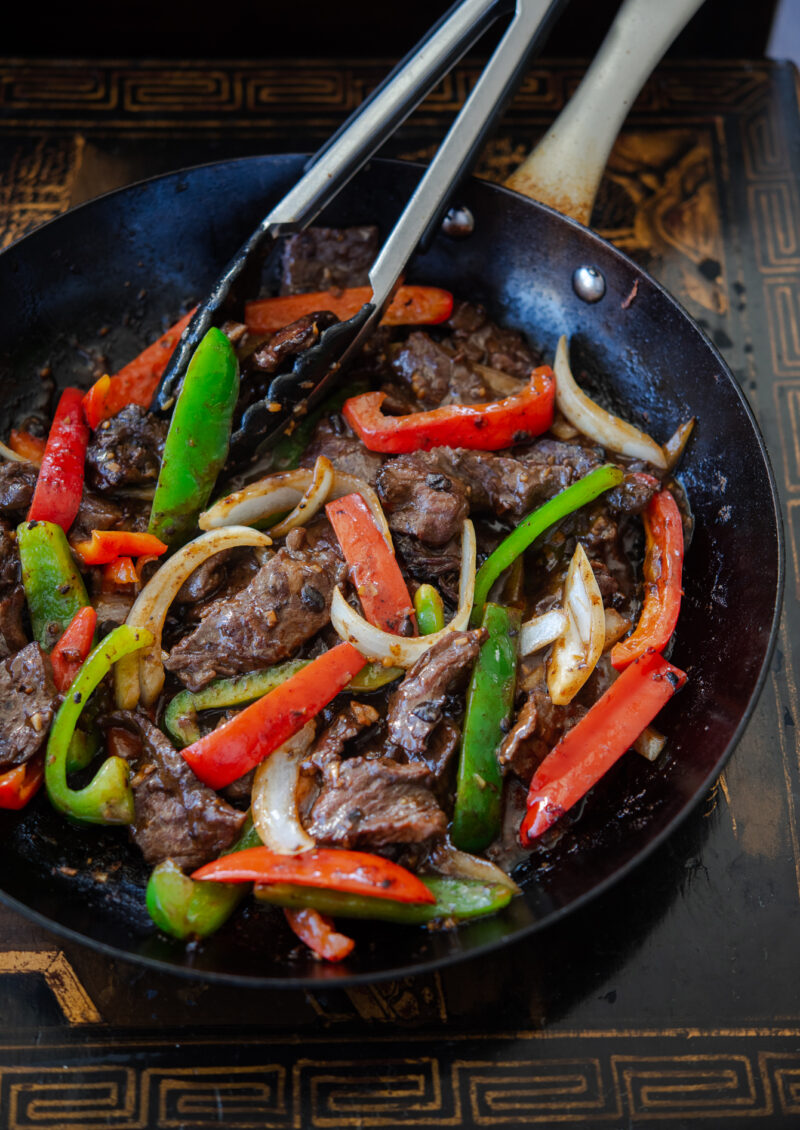 A skillet filled with stir-fried beef and peppers.
