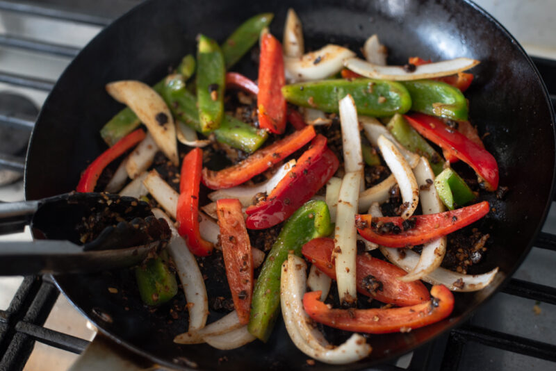 red and green peppers, onion stir frying with savory ingredients.