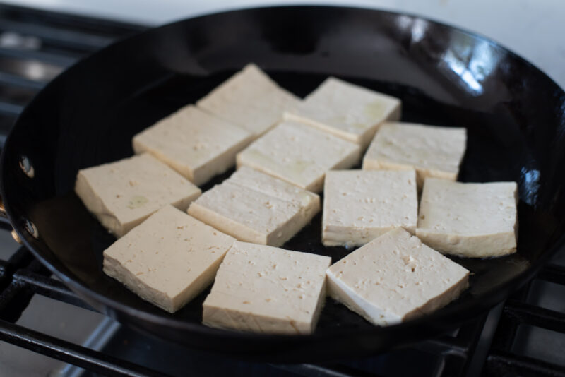 Pan-fry tofu slices in hot oil until golden crisp.
