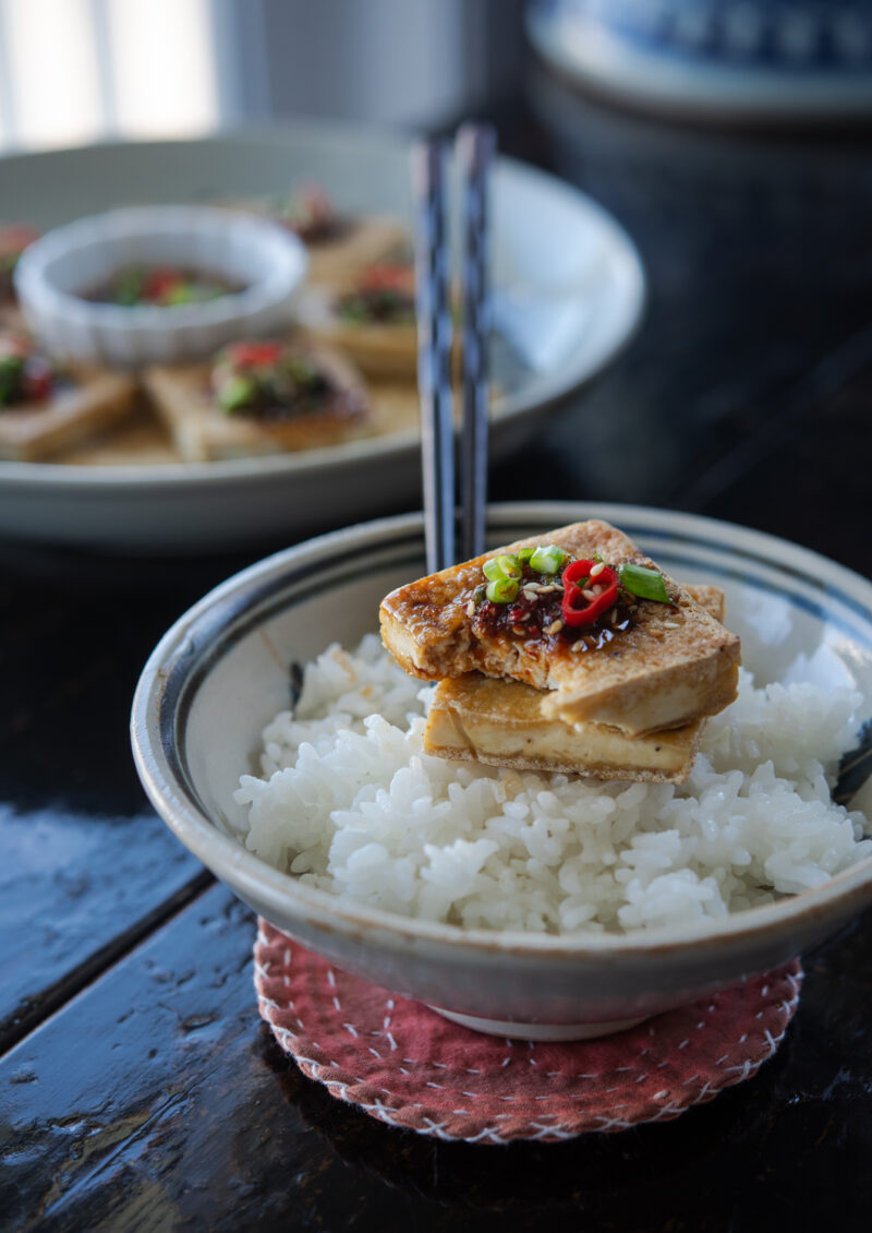 Crispy pan-fried tofu with soy chili sauce is served over white rice