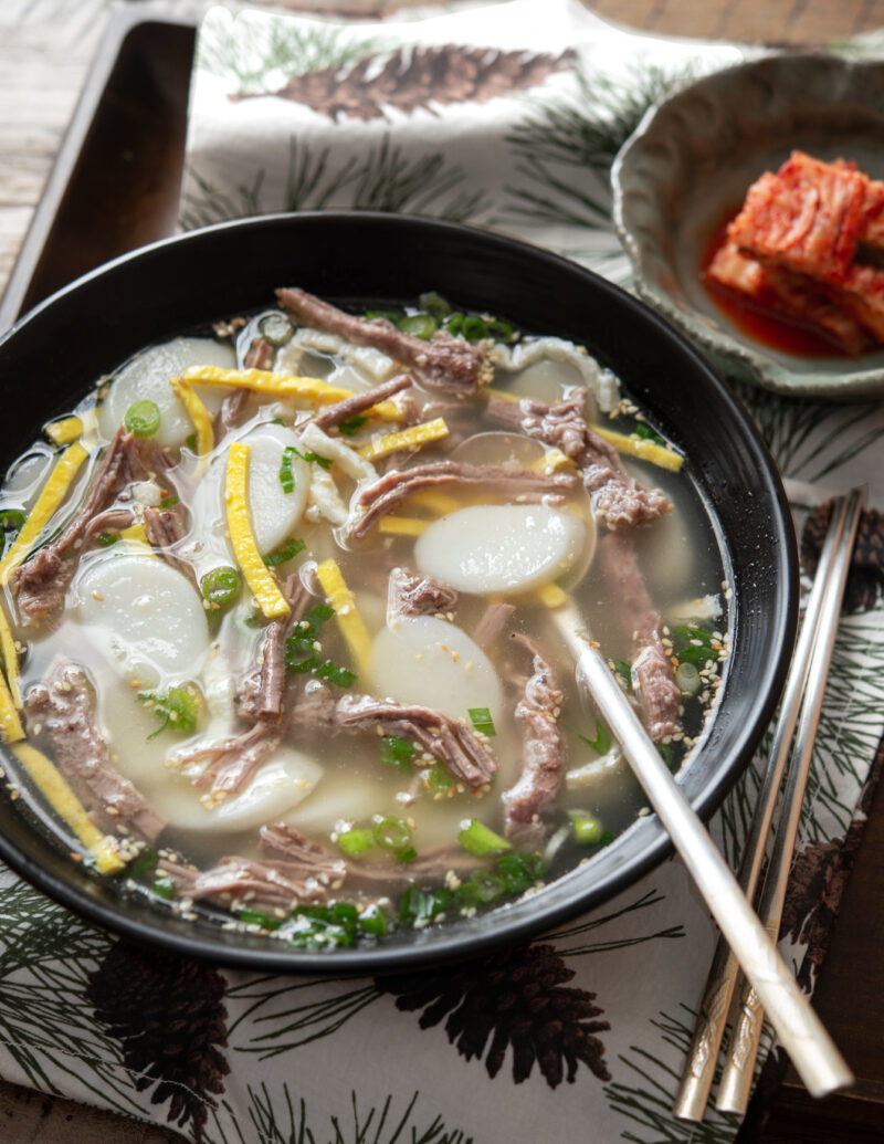 This Korean rice cake soup has a clear beef broth and sesrved with kimchi
