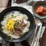 Tteokguk, Koran rice cake soup in a bowl, garnished with eggs.