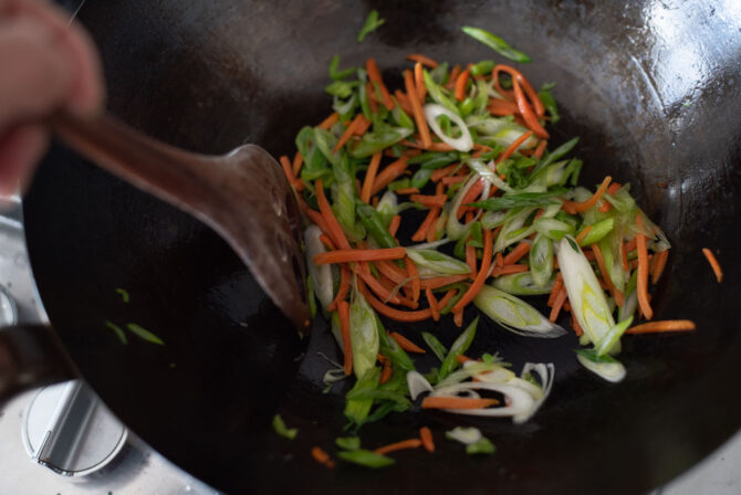 Onion and green onion are fried in a skillet