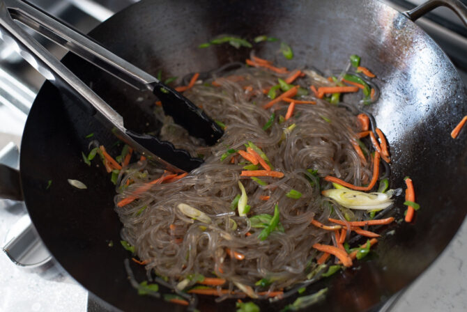 Glass noodles are added to the vegetables and seasoned with condiments.