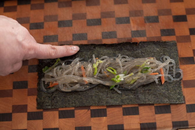 Noodle filling is placed on top of seaweed sheet and dab water with a finger.