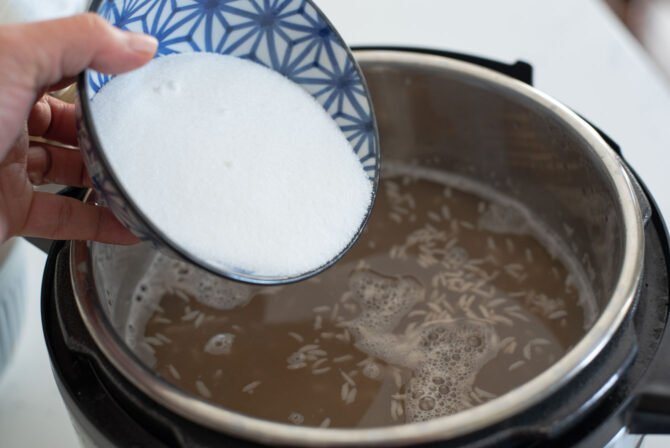 Sugar is added to the fermented Kroean rice punch in an instant pot.
