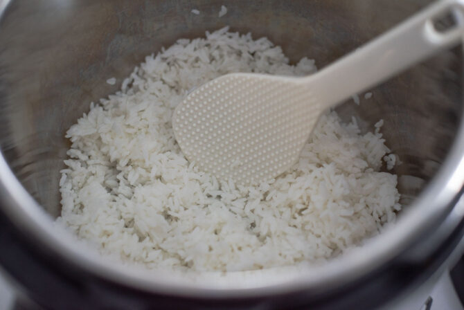 Cooked rice is added to the instant pot and broken up with a spatula