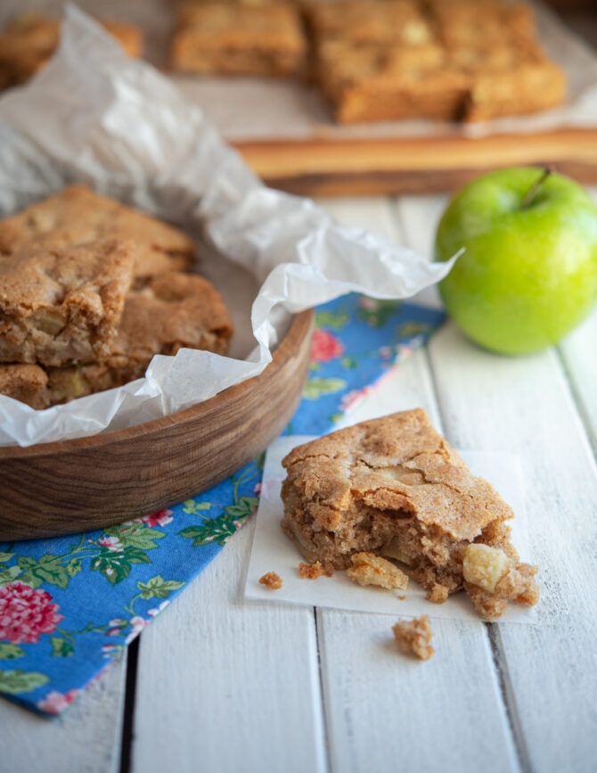 A slice of apple brownies shows the moist texture inside with lots of apple pieces
