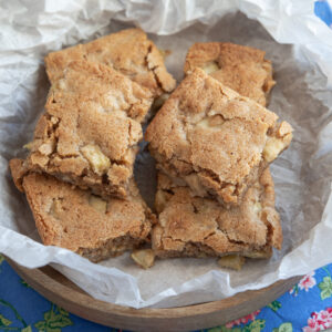 Slices of apple brownies are placed in a bowl lined with white parchment paper.