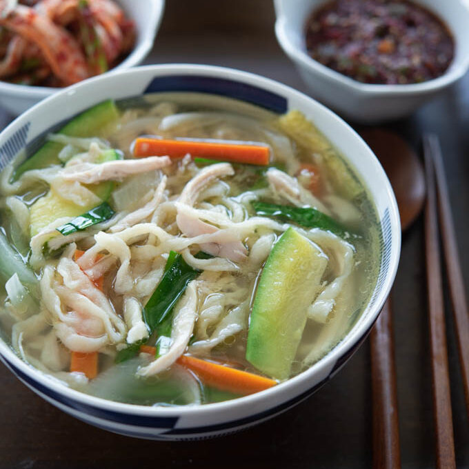 Korean knife cut noodle soup is cooked with chicken, zucchini and carrot in Korean herb broth.