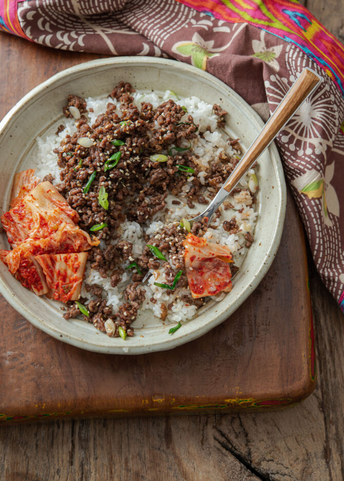 A plate of rice, ground beef bulgogi, and kimchi are served together.