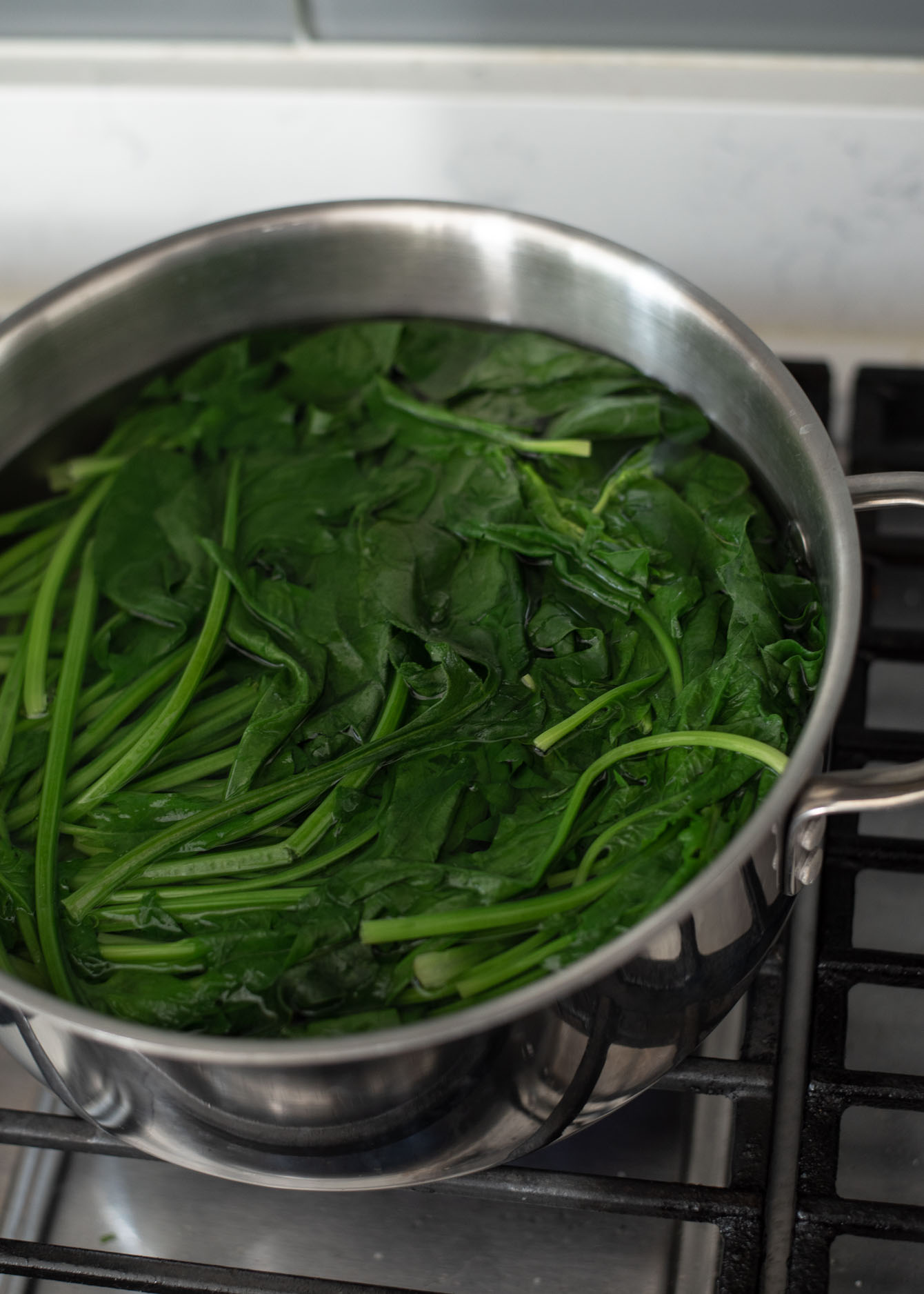 A bunch of spinach is blanching in a pot of hot water