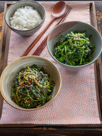 Two Korean spinach side dishes are served with rice on a tray.