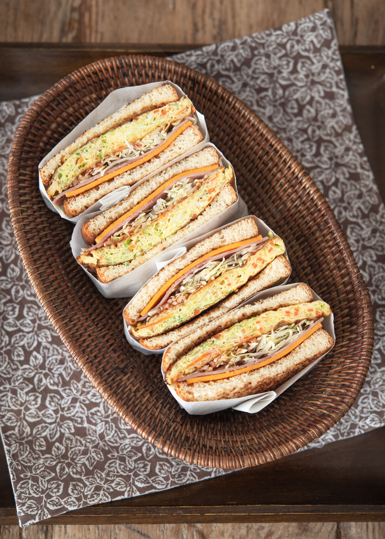 Korean street toast sandwiches are sliced in half and place in a weaved basket dish.