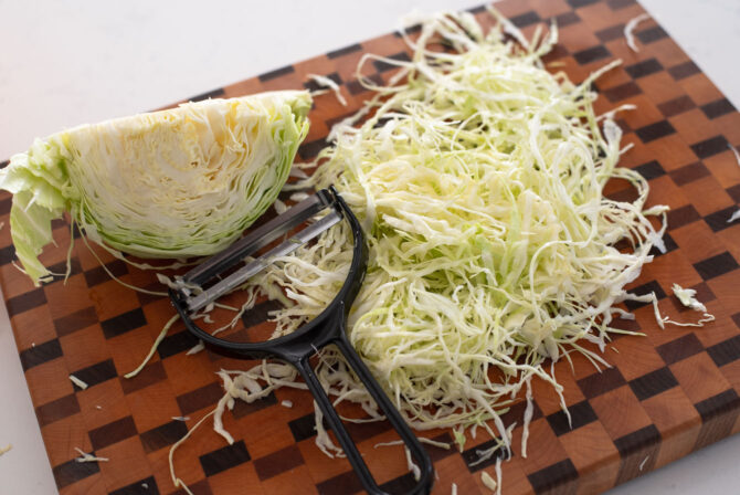 Green cabbage is finely shredded with a vegetable peeler.