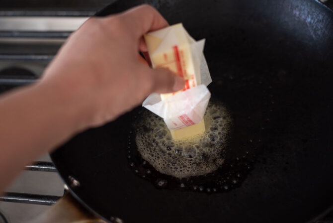 Using a stick of butter to melt and coat the pan.