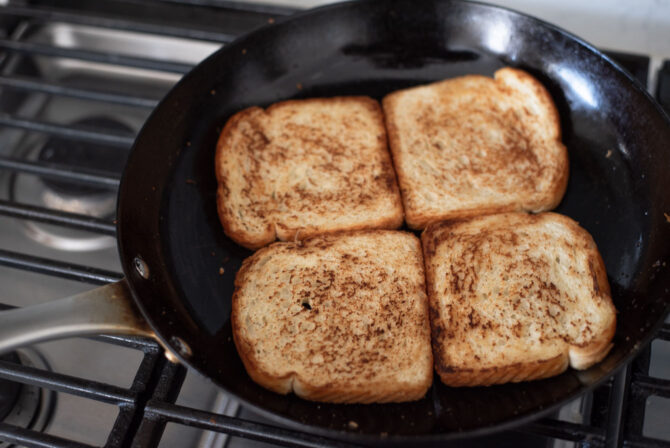 Bread slices are toasting in a skillet with butter in a skillet.