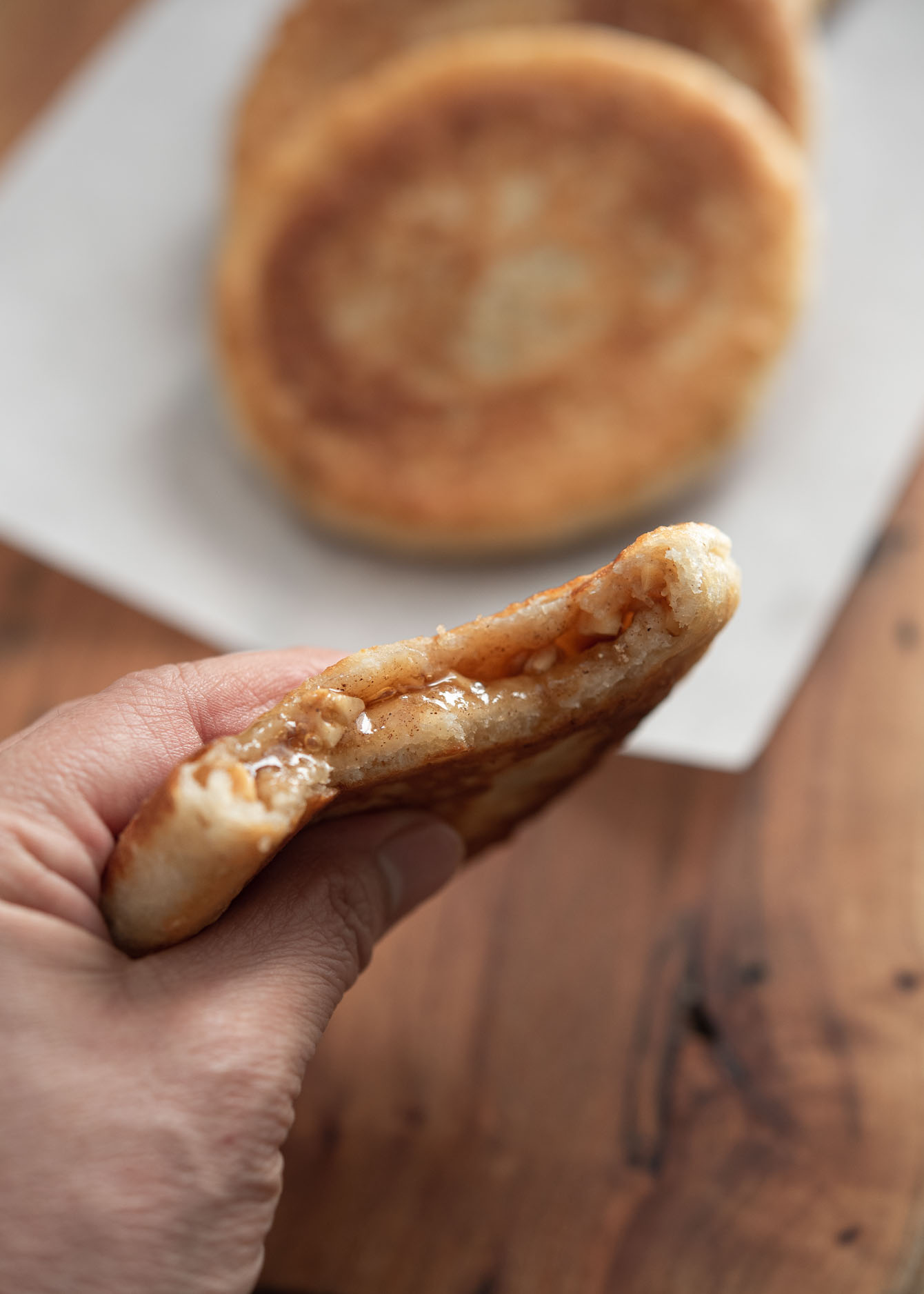 A hand holding a slice of Korean sweet rice pancake is showing hot brown sugar syrup inside.