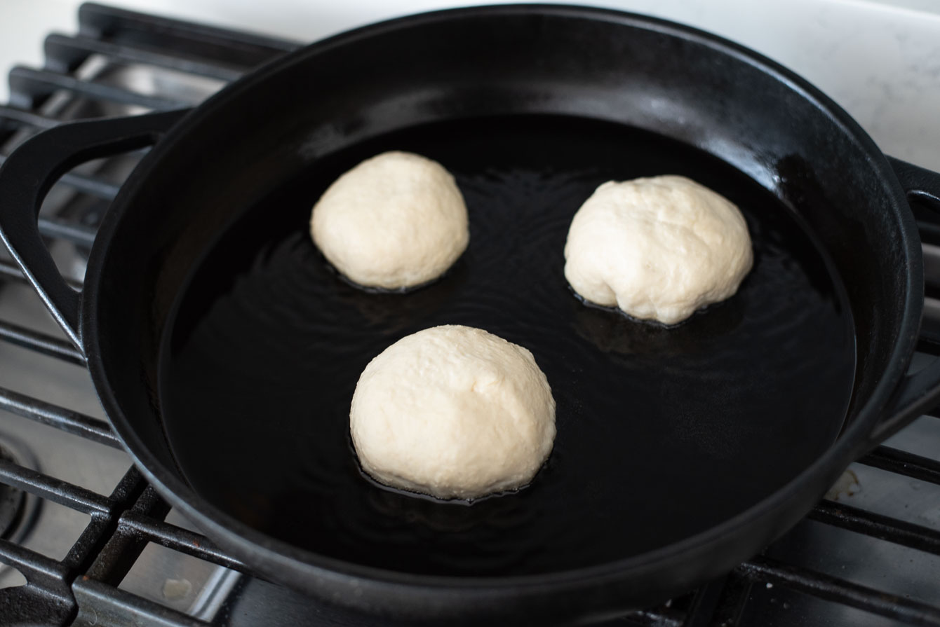 Three hotteok doughs placed on a hot griddle to fry.