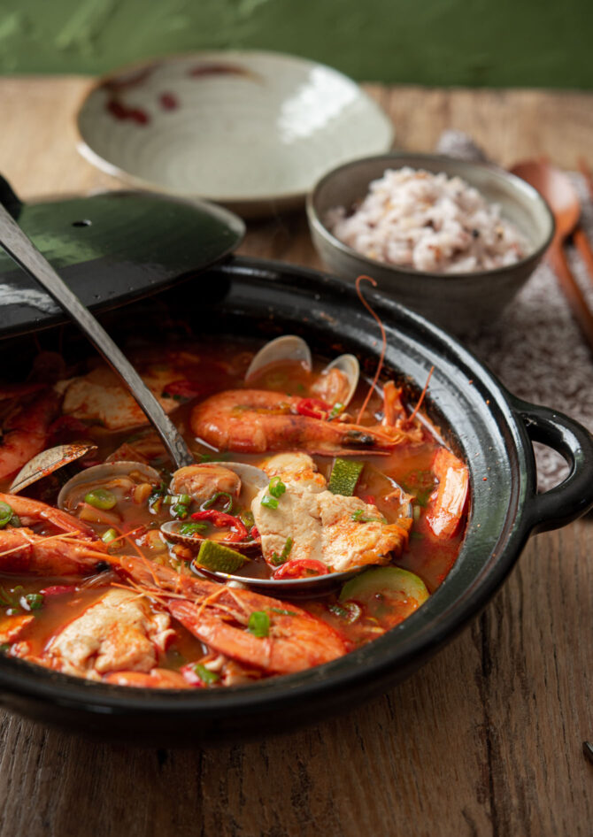 Korean soft tofu soup with seafood is cooked in a stone pot.