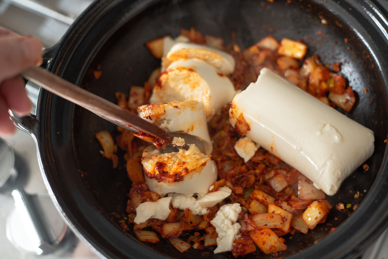 Soon tofu is added to onion kimchi mixture in chili oil.