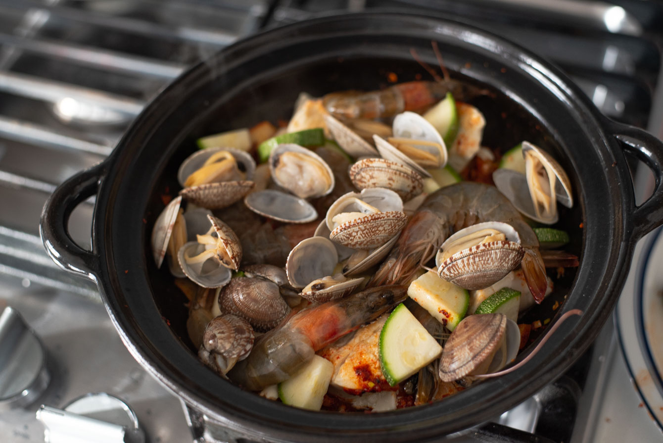 Seafood and zucchini are added to the pot to make soondubu jjigae.