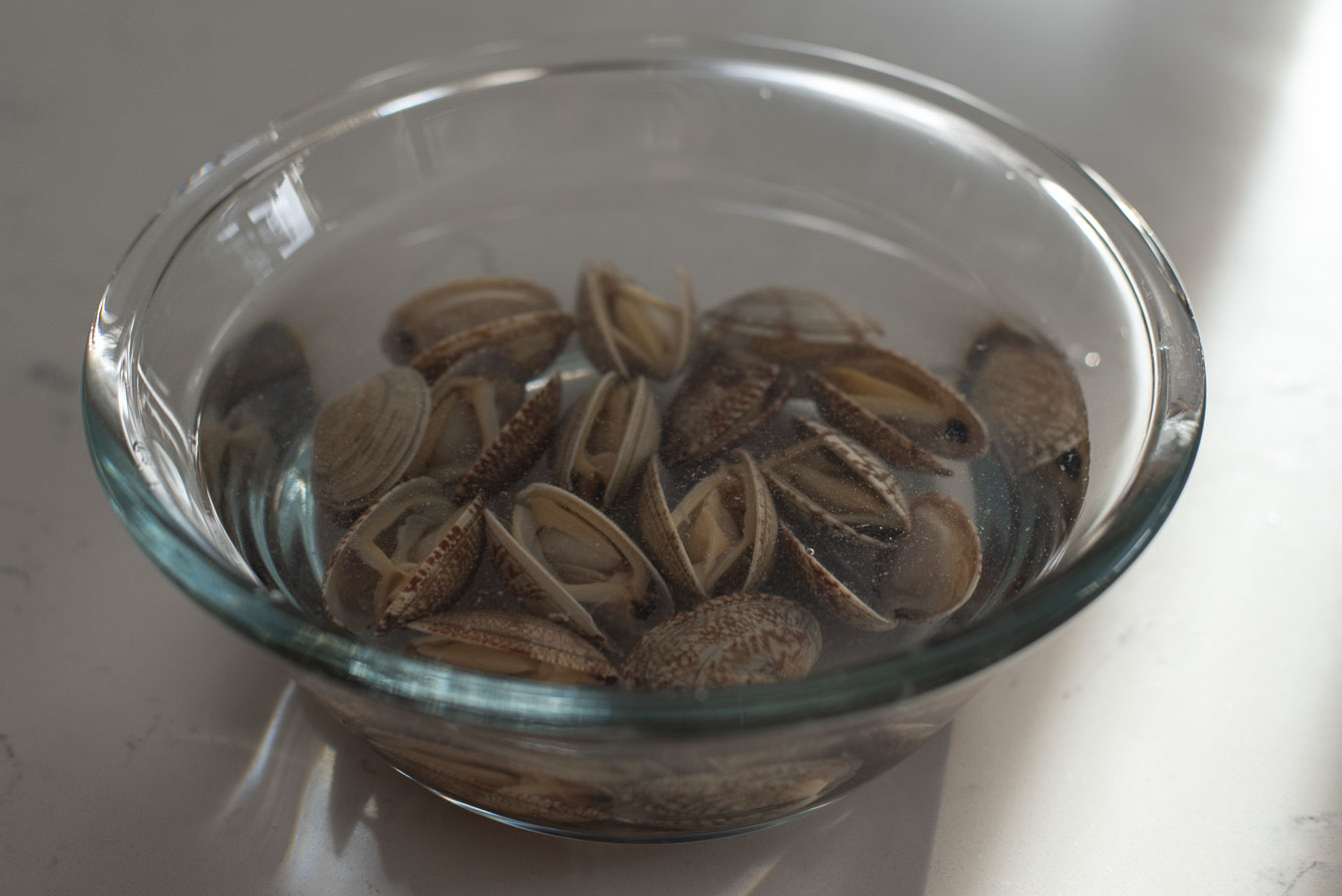 Frozen clams soaking in a bowl of cold water
