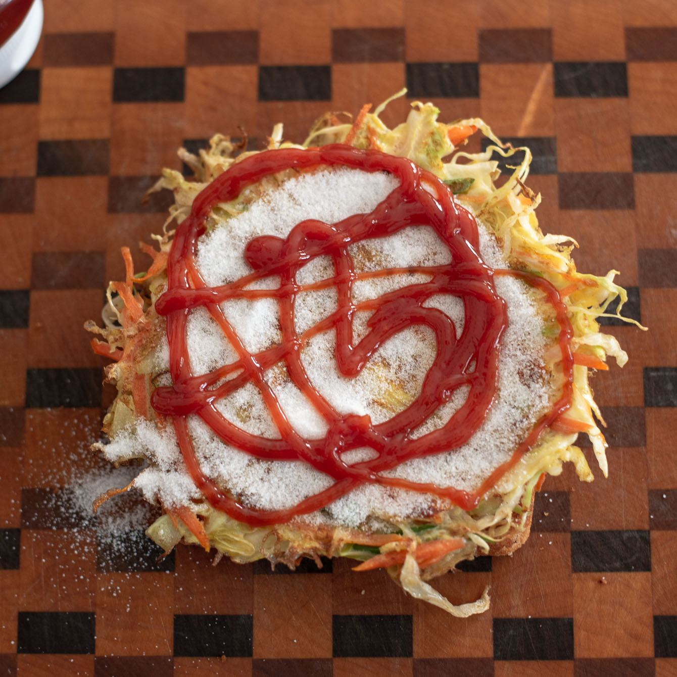 Ketchup is squirted on top of sugar with egg omelette for Korean street toast.