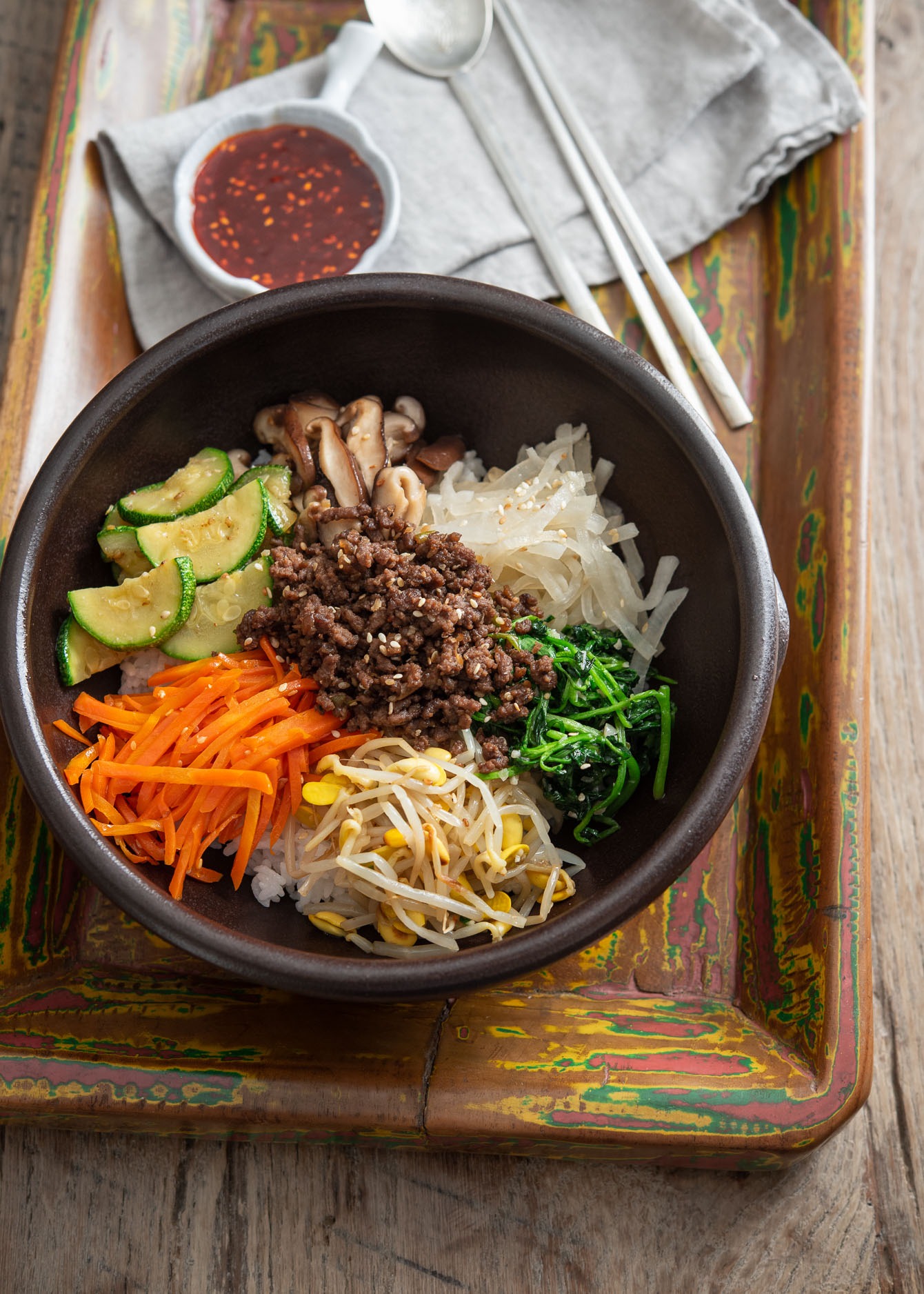 Bibimbap bowl arranged with colorful vegetables and ground beef bulgogi over rice.