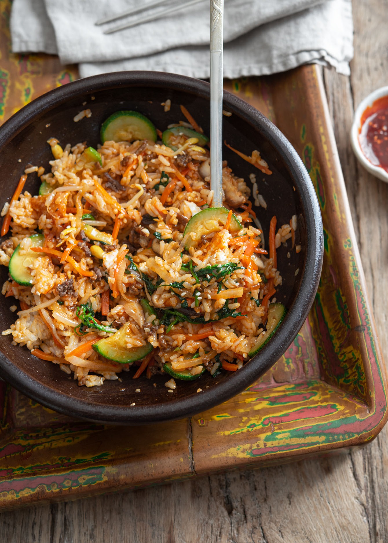 Top view of bibimbap mixed in a stone bowl with a spoon.